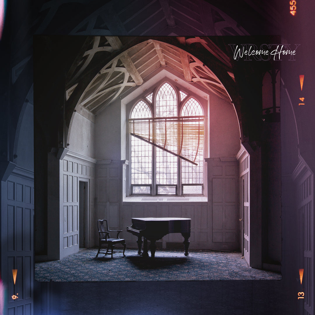 A VRSTY grand piano and a single chair sit before a tall arched window with sunlight flooding the spacious room. Exposed wooden beams and white paneled walls frame the phrase “Welcome Home” in the corner.