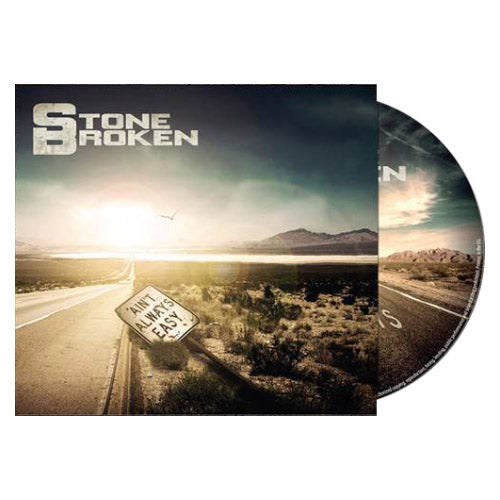 The Stone Broken CD cover features a desert road at sunrise, a tilted Aint Always Easy sign, mountains and bright sky in the background, with the Heartbeat Away CD partially visible behind the cover.