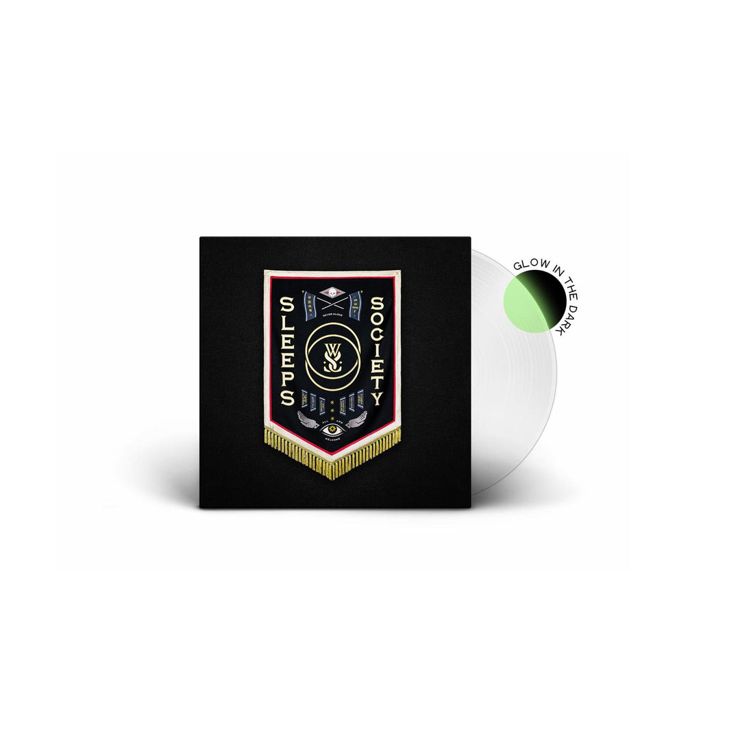 A white vinyl record with a green glow-in-the-dark section slides out of a black sleeve displaying a colorful embroidered patch design, Sleeps Society text, tracklist, and the brand name While She Sleeps.
