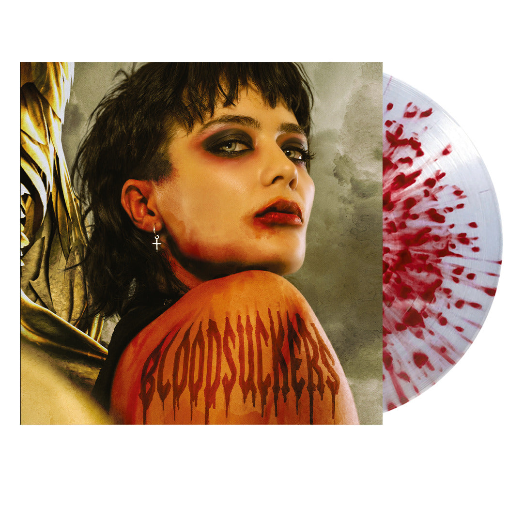 A red splatter vinyl record peeks out from behind the Saint Agnes BLOODSUCKERS album cover, featuring dramatic makeup, bold earrings, and “BLOODSUCKERS” scrawled in blood-red letters across a shoulder.
