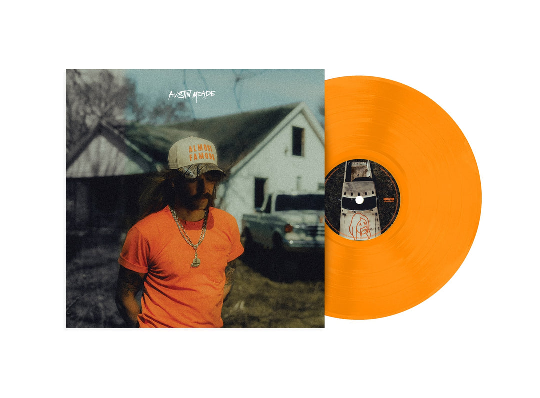 A bright orange vinyl LP by Austin Meade slides out of an album cover showing a long-haired, mustached man in sunglasses, “Almost Famous” cap, and red shirt by a house and car—a must-have for Almost Famous vinyl collectors.