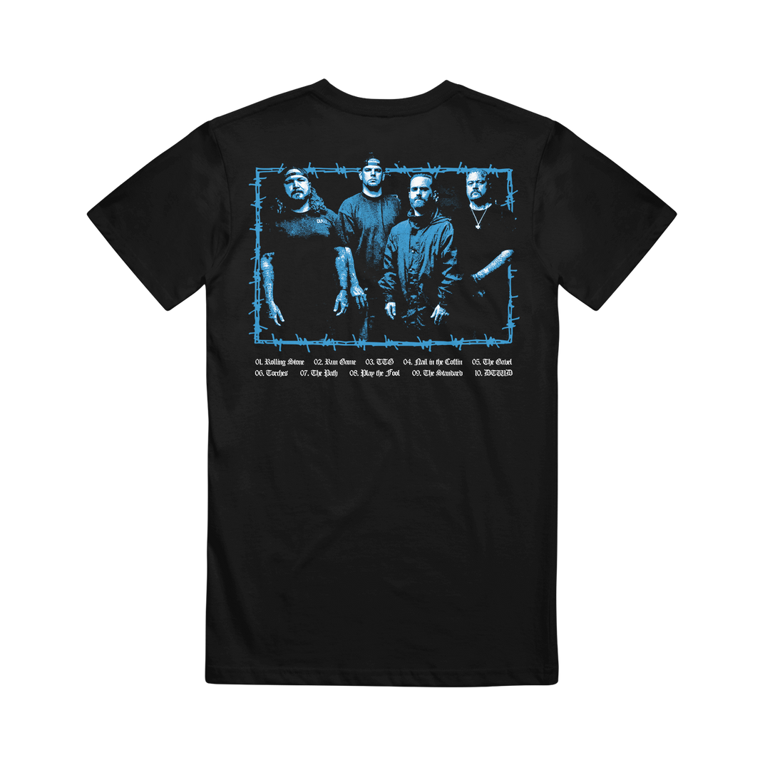 The Southpaw FLHC Photo Black T-shirt features a blue-tinted image of four men standing together on the back, framed in barbed wire, with white song titles listed below.