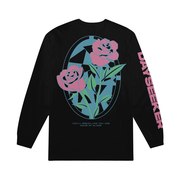 back of dayseeker stained glass black long sleeve. on the entire back is two large roses in a stained glass style in pink and green ink, under the roses the text "you'll break like you are made of glass" in blue text. dayseeker in large pink text printed down the right sleeve. 