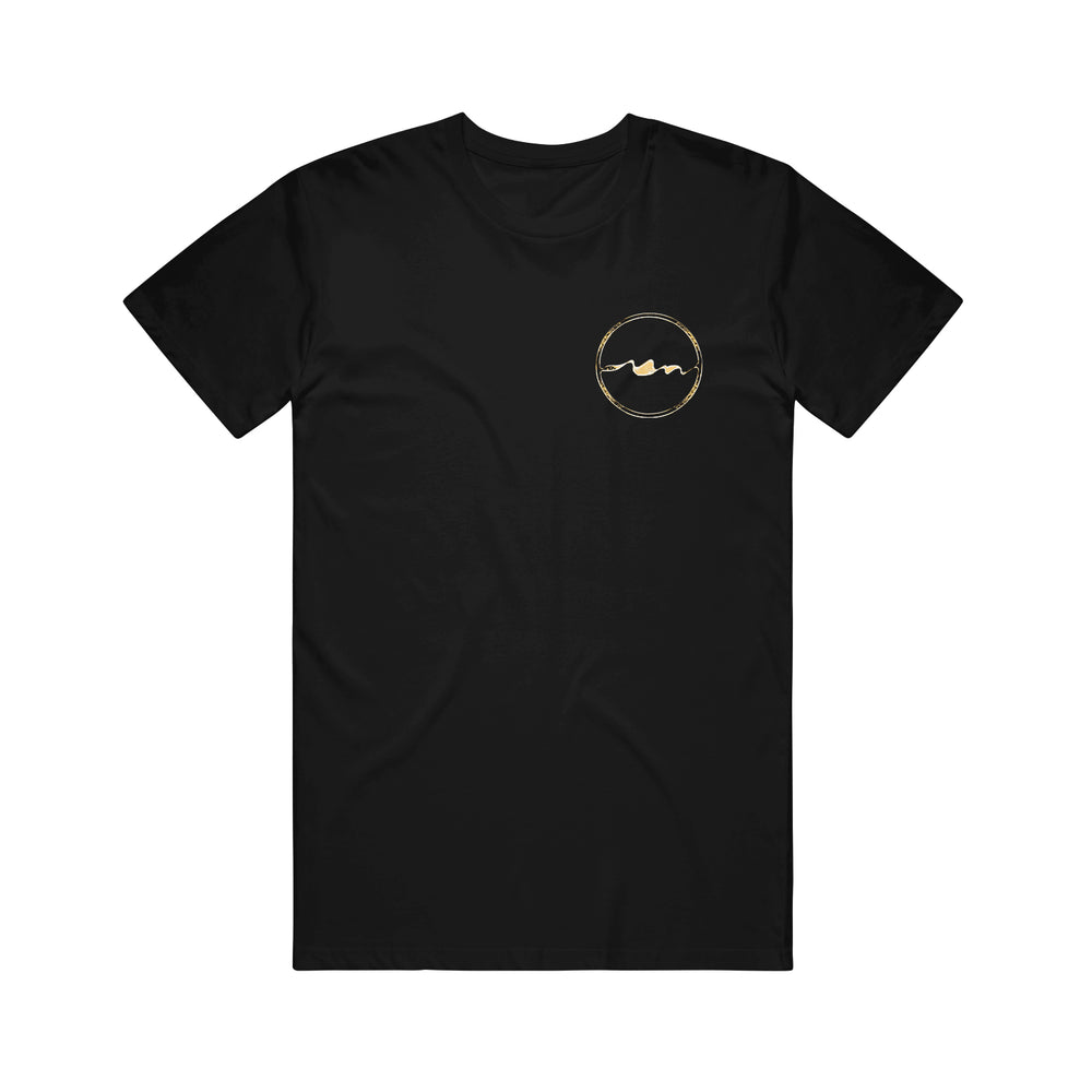 Unprocessed black t-shirt in a classic fit, made from Gildan Heavy Cotton 100% cotton. Left chest features a small gold circular emblem with a minimalist wavy line design inside.
