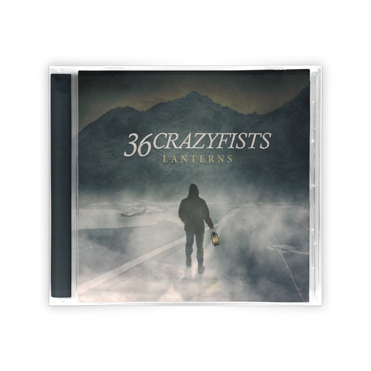 image of a jewel case cd on a white background. album cover in the ceter says 36 crazyfists lanterns. there is a man walking by water in front of mountains holding a lantern