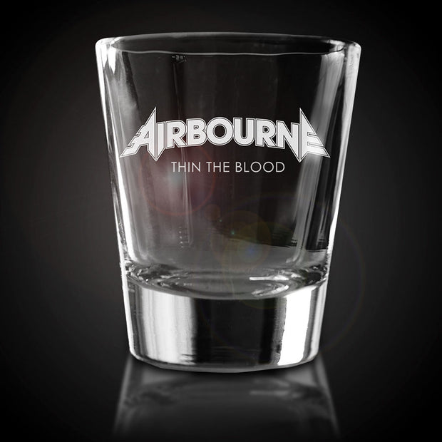 image of a glass shot glass on a black background. in white print, it says airbourne. below that says thin the blood