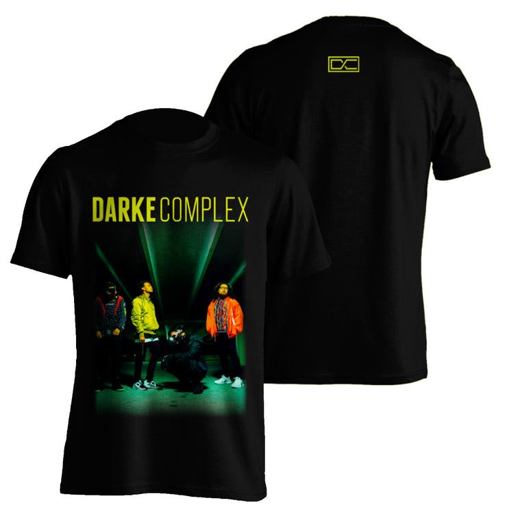image of the front and back of a black tee shirt on a white background. front has color image of the band members and darke complex across the top. the back has a small yellow print at the top center of the letters D C